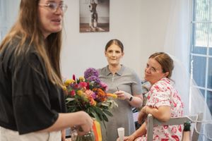 Group gathered around a floral arrangement during an indoor workshop or event.