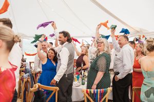 A festive celebration under a tent with colorful decorations and guests enjoying the party atmosphere.