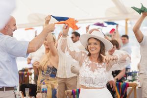 Festive celebration under a white tent with people dancing and raising their hands in joyous celebration.