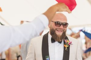 A joyful guest in a bowtie and sunglasses enjoying a celebratory moment at an outdoor event.