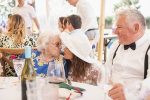 Wedding reception guests enjoy conversation at a decorated outdoor table setting.