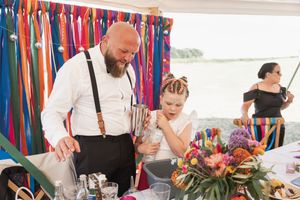 Colorful streamers decorate a bar area where drinks are being prepared at an outdoor event.