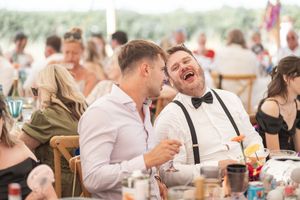 Two wedding guests share a laugh during the reception while seated at their table.
