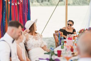 Guests seated at a table decorated with colorful streamers during an outdoor celebration.