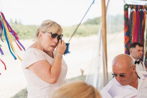 Wedding guests enjoying themselves under a decorated tent with colorful streamers and ribbons.
