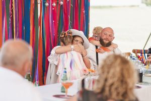 Vibrant red and blue ribbons hang as decorative elements at an outdoor wedding celebration.