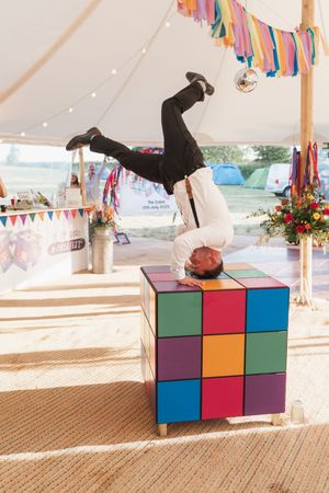 An acrobatic breakdancing performance on colorful blocks under a white tent at an outdoor event.