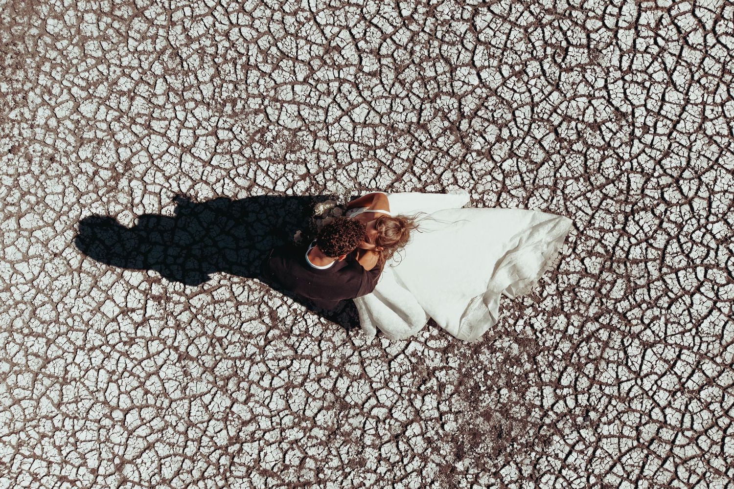Romantic desert wedding photography session against rolling sand dunes and blue sky.