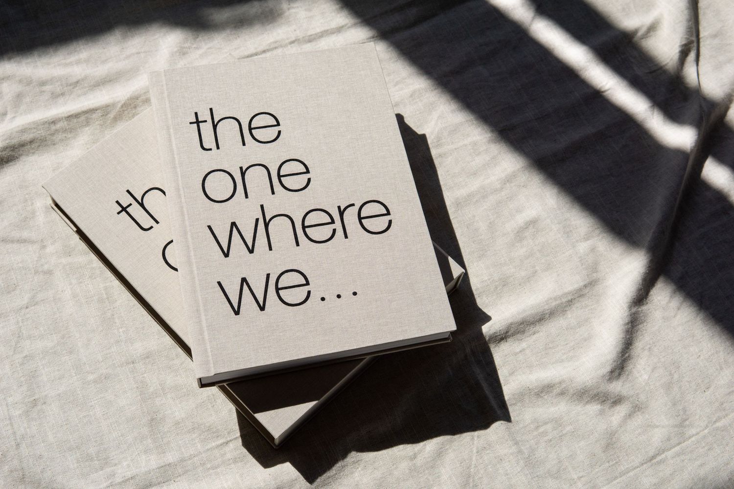 Minimalist white card with black text reading 'the one where we...' casting dramatic shadows.