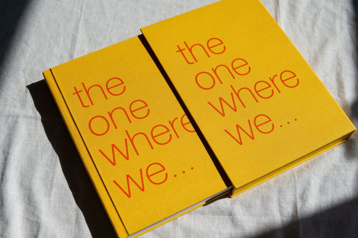 Two matching yellow books with red text reading 'the one where we...' on white bedding.