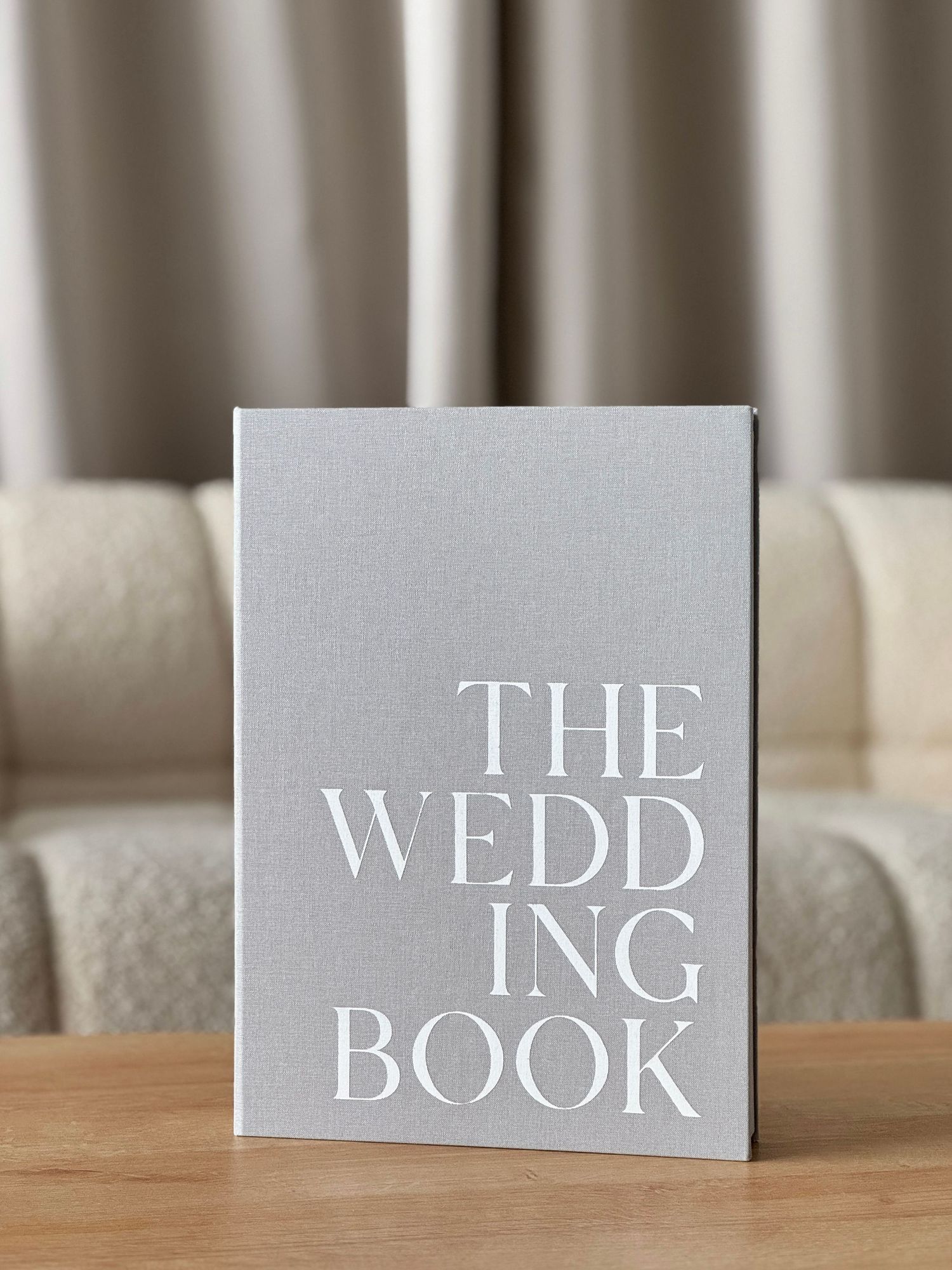 Three white letterpress cards displayed side by side with the text THE WEDD BOOK in elegant silver lettering on a table surface.