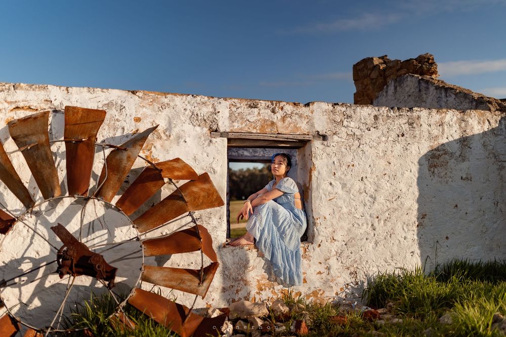 Rusty metal and white stucco walls create an abstract architectural composition against a bright blue sky.