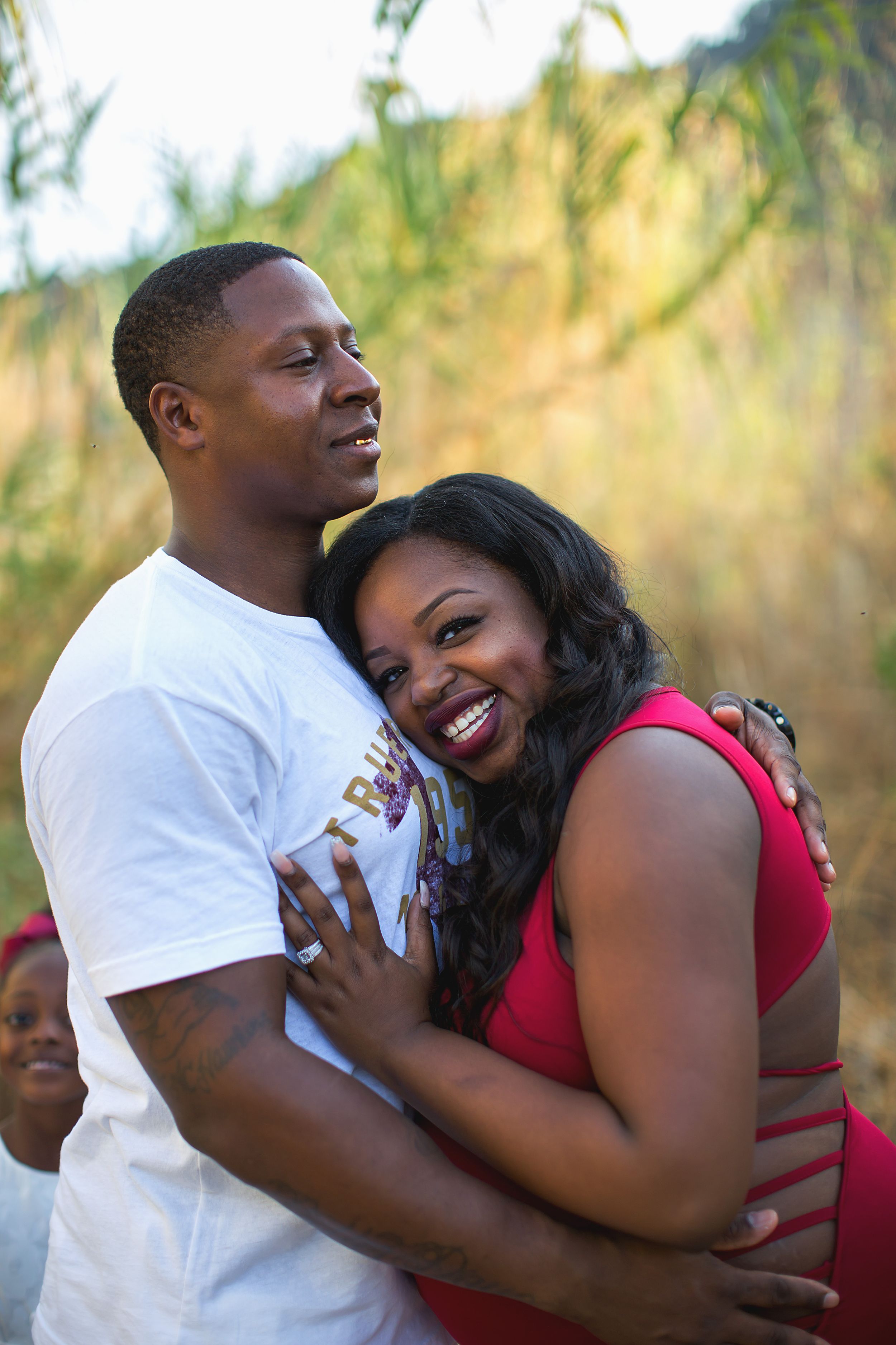 A couple shares joyful laughter during their engagement photoshoot in a natural setting.