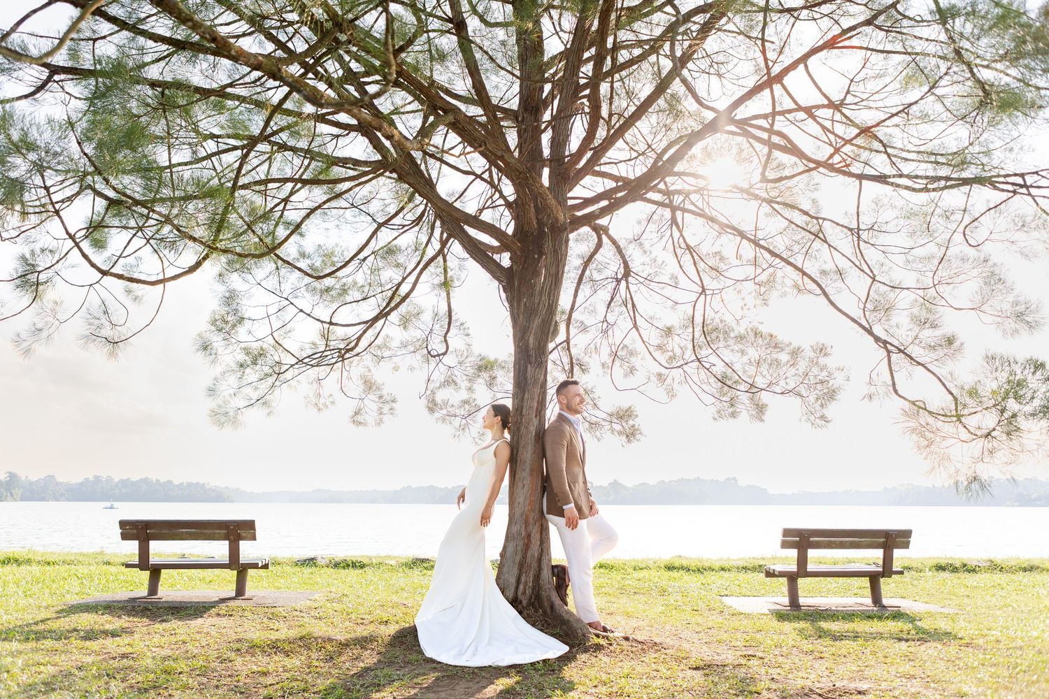 wedding couple under the famous Upper Seletar Lone Tree with a gorgeous orange Sunset and a body of water behind them