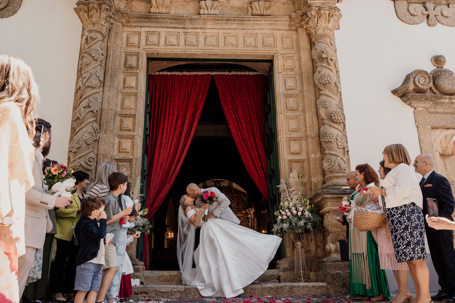 Wedding party members in turquoise and neutral dresses gather under ornate church archways.