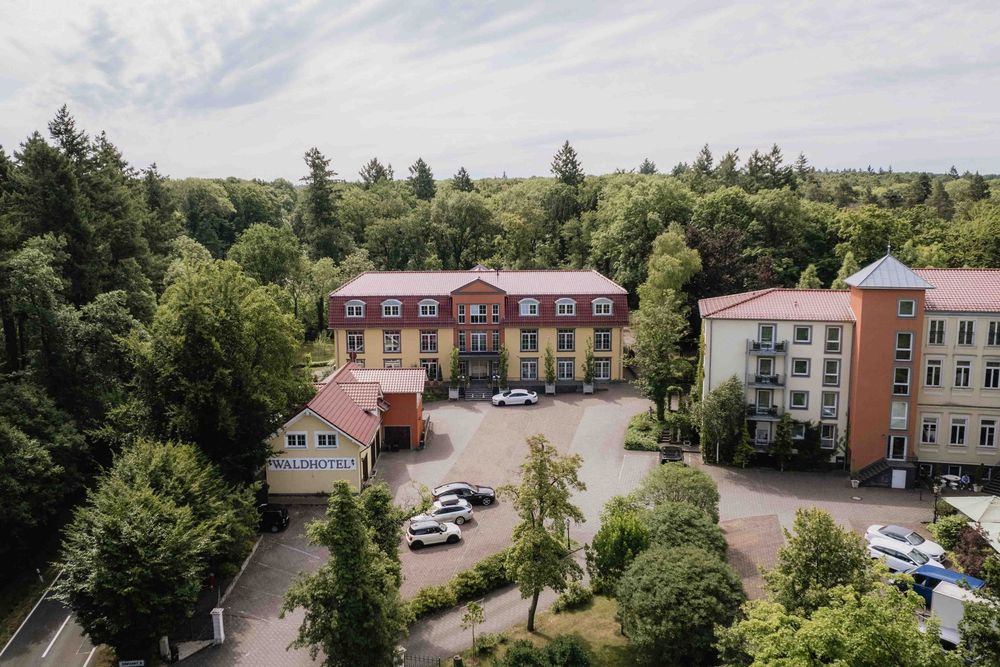 Aerial view of a red brick hotel building surrounded by trees and parking lots.