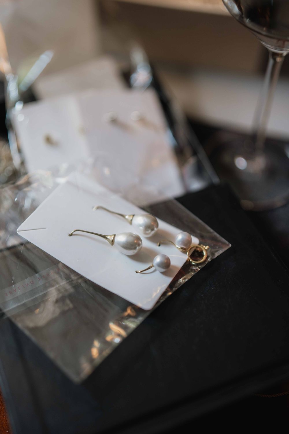 Pearl earrings displayed on white cards against a reflective surface.