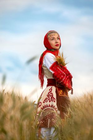 Series of dynamic poses in a wheat field wearing traditional red and white folk costume.