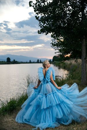 Dramatic photos of flowing blue princess gown against lakeside sunset.