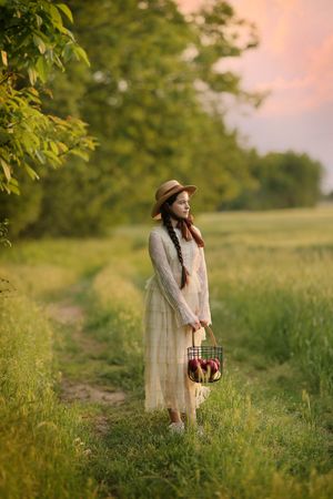 Pastoral scenes in a meadow at sunset with vintage-style dress and basket.