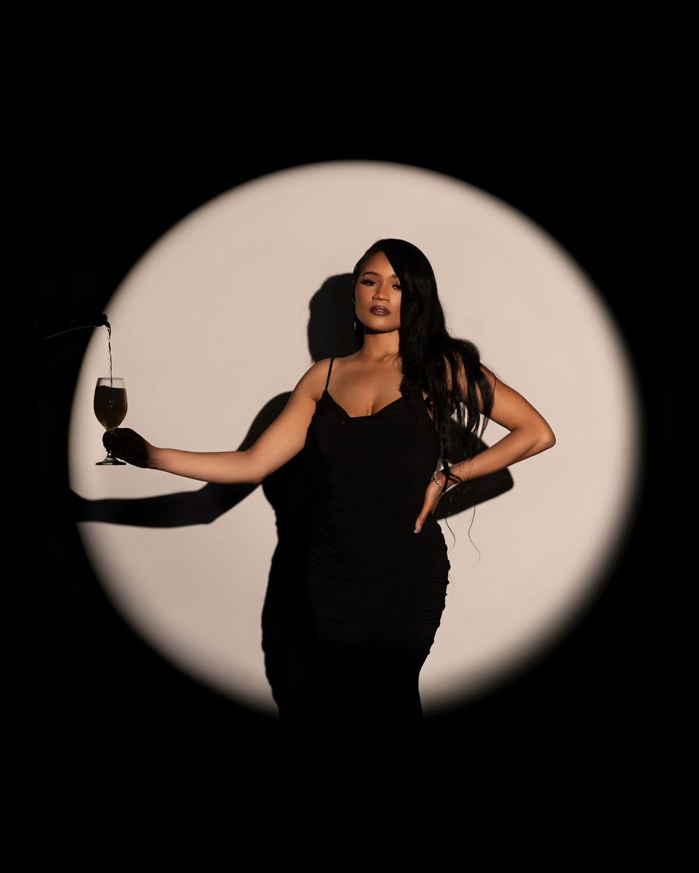 Artistic silhouette poses in dramatic spotlight against dark background.