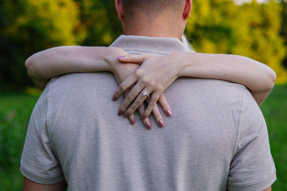 Back view of someone wearing a gray t-shirt being embraced from behind.