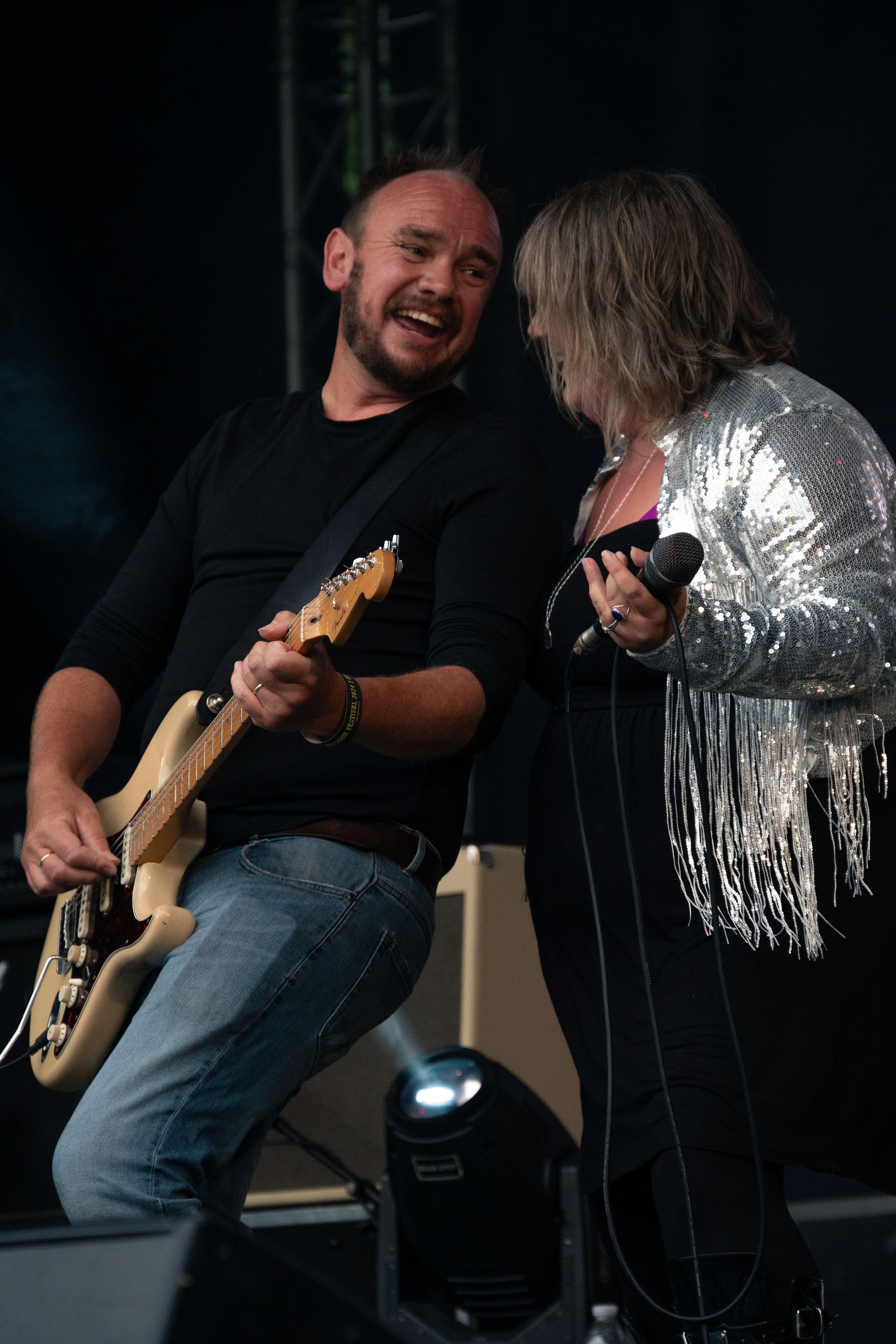 Musicians performing together on stage with guitars during a live concert performance.