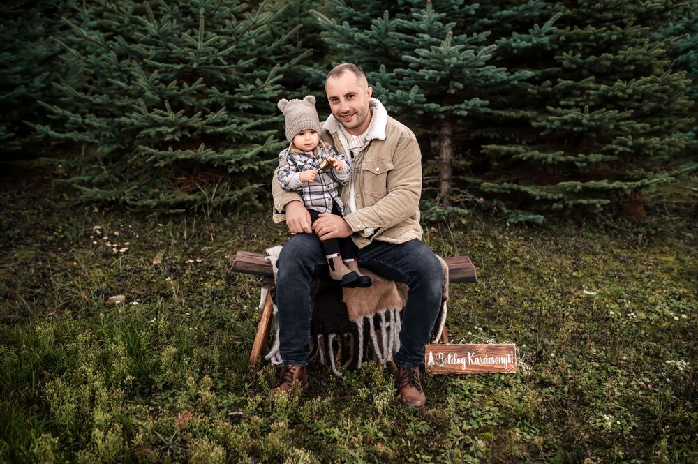 Cozy fall portrait session among tall evergreen trees with rustic wooden sign.