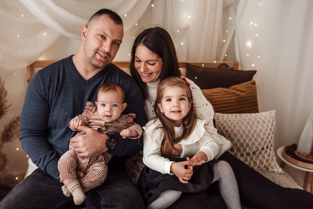 Warm indoor family portrait with fairy lights and neutral decor.