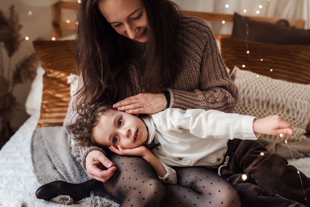 Playful moment captured on cozy bed with warm lighting and textured pillows.