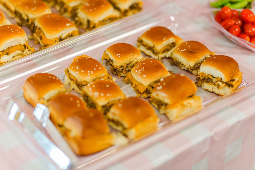 Golden brown mini sliders arranged neatly in rows on a clear serving platter.