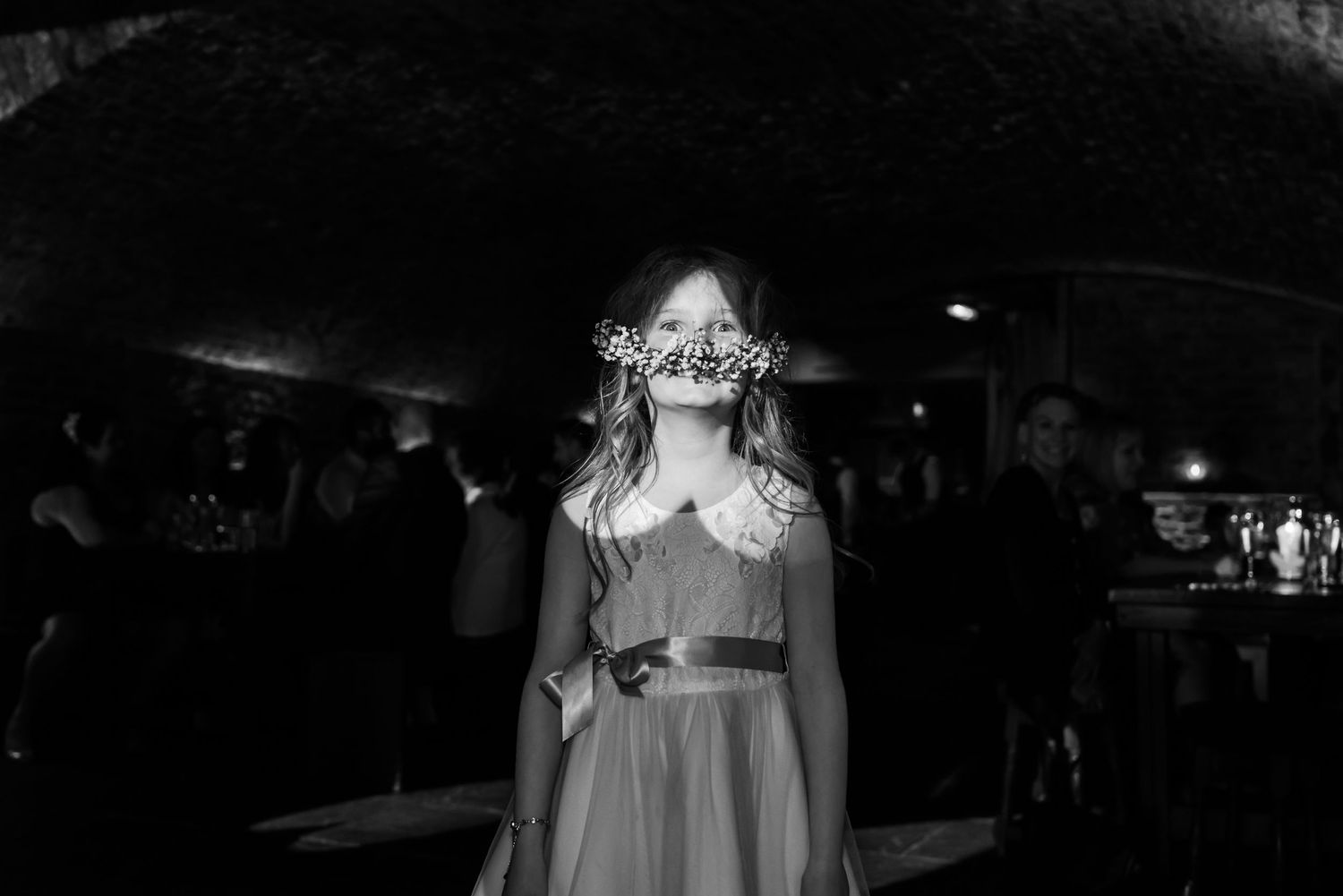 A dreamy black and white portrait in an atmospheric cellar setting with dramatic lighting.