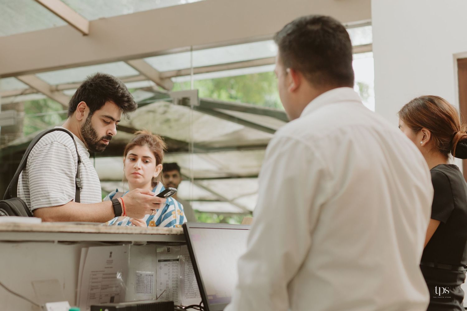 Service counter interaction in an outdoor setting with natural lighting and foliage.