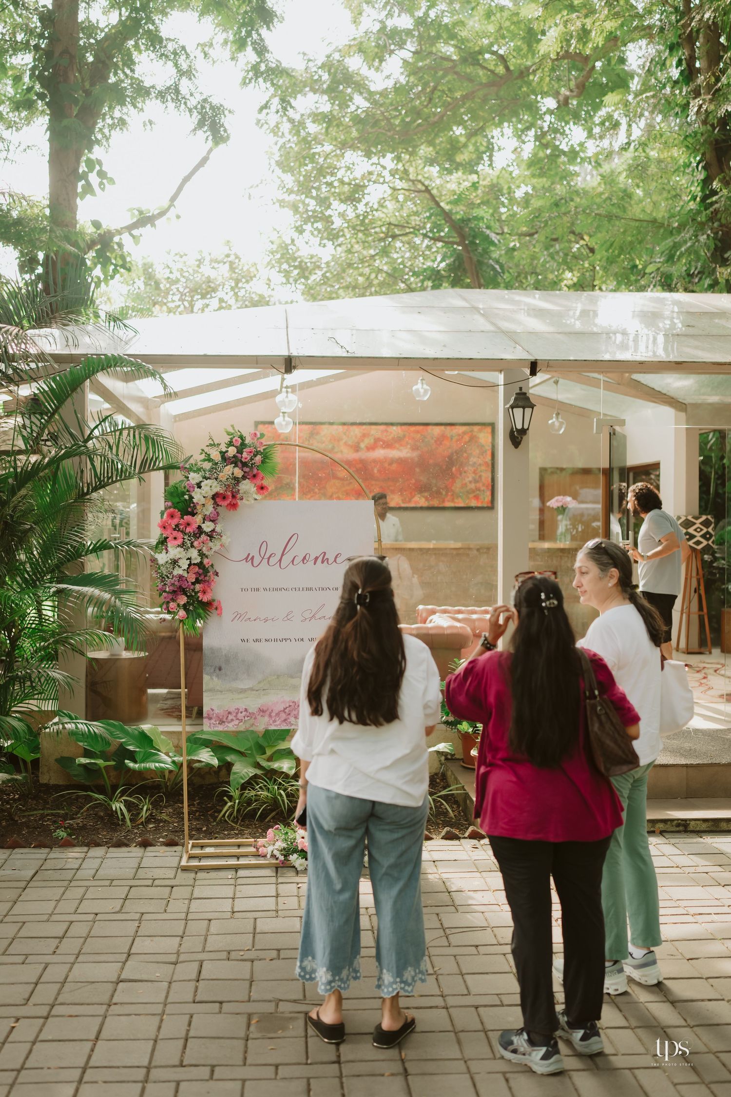 Group of people viewing displays at an outdoor venue with greenery and welcome signage.