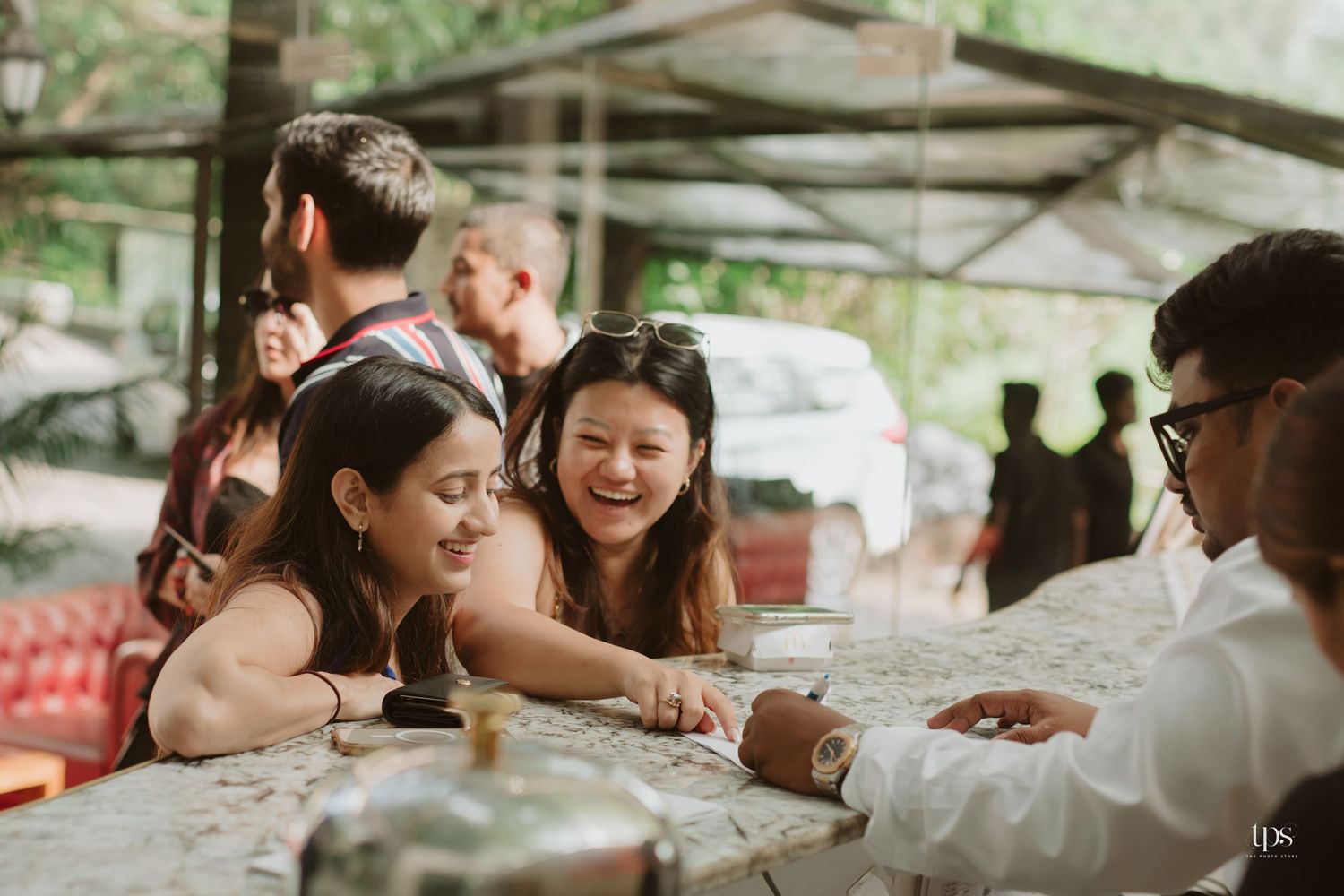 Casual gathering at an outdoor venue with people interacting around tables.