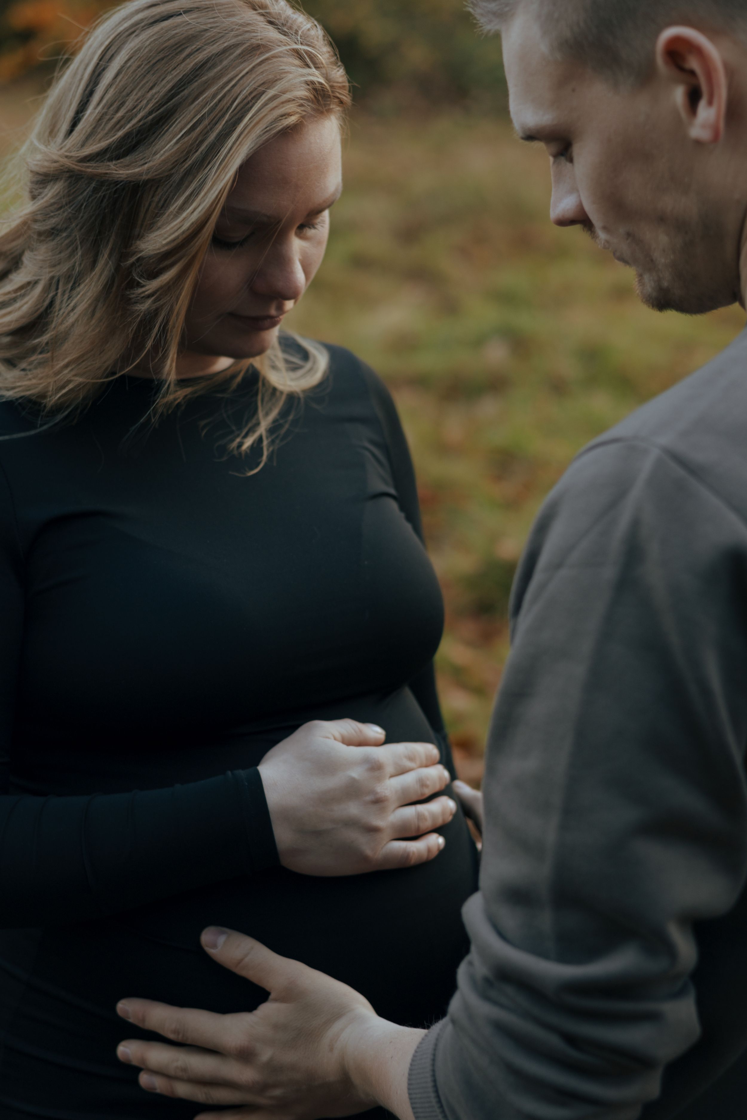 An intimate maternity portrait showing gentle hands resting on a baby bump.
