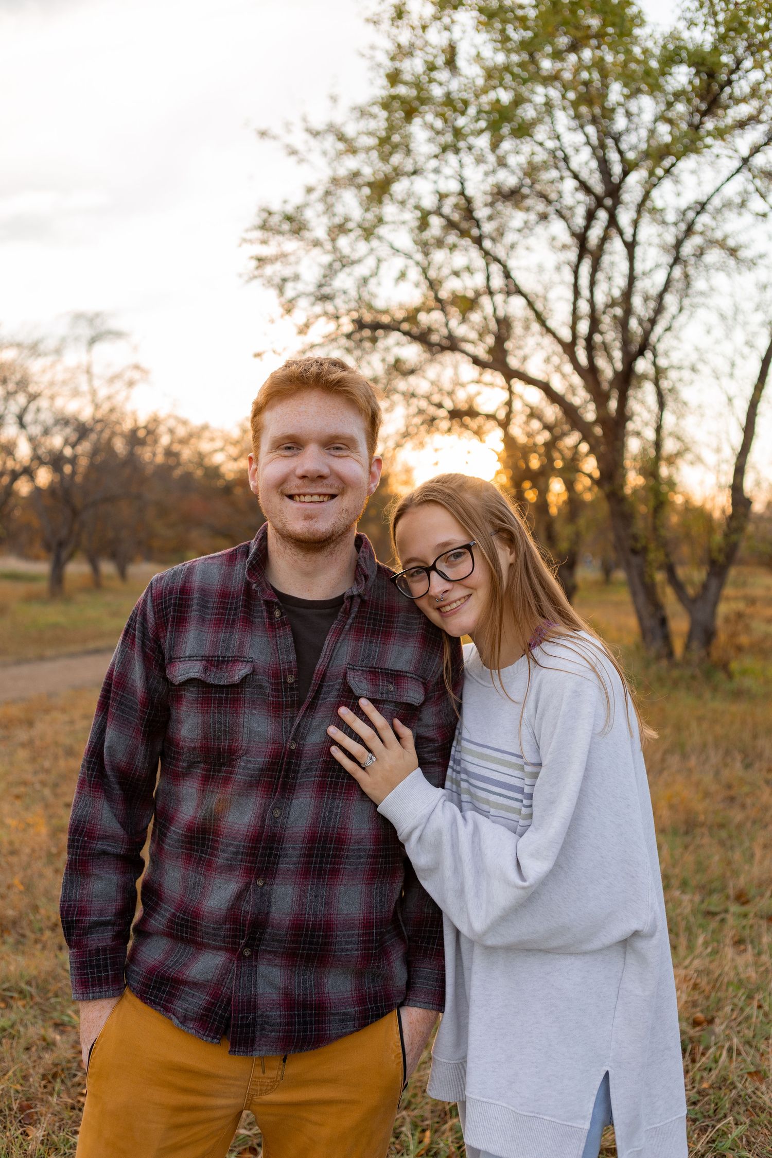 Couple in casual fall outfits smiling together in autumn field.