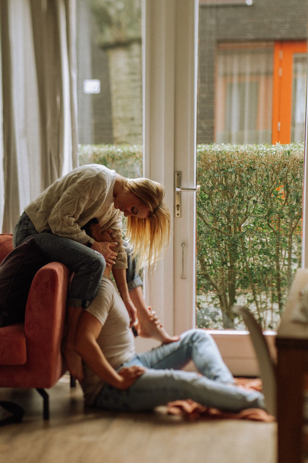 Intimate couple lounging together by bright windows in casual home setting.