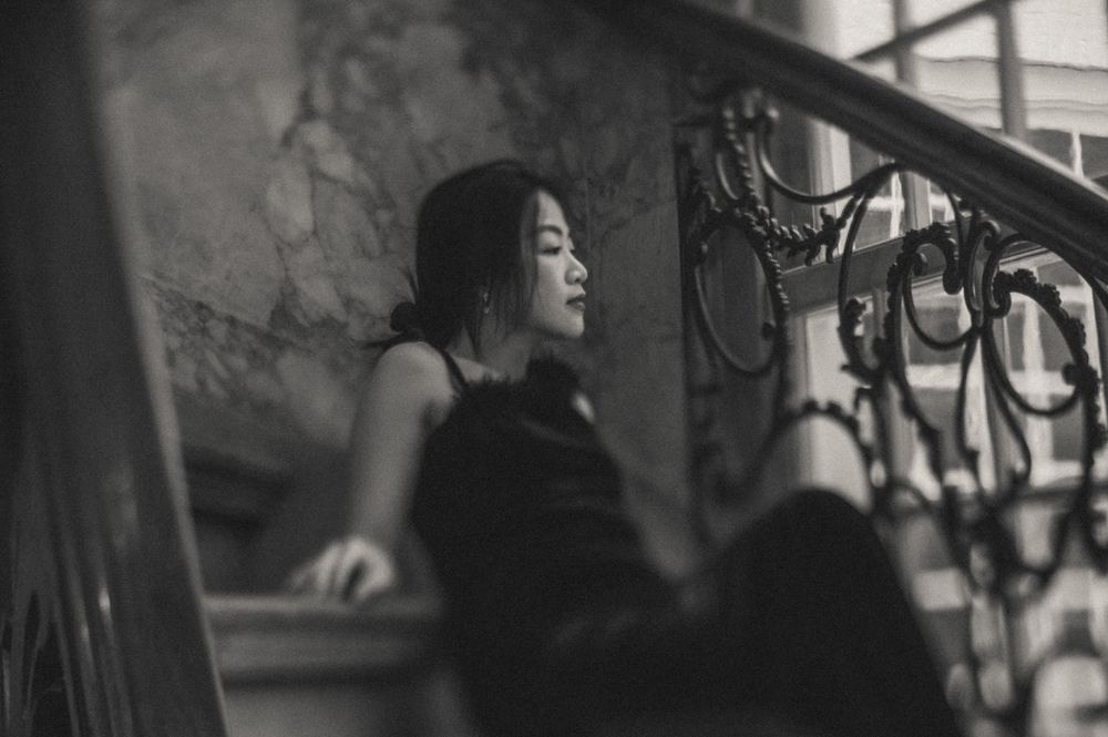 Silhouette against wrought iron railings in dramatic lighting.