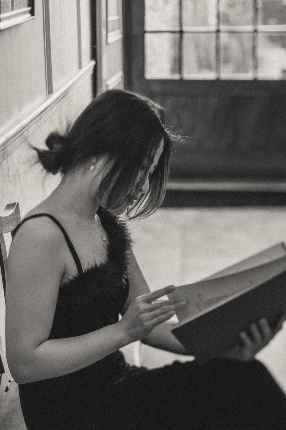A series of black and white photos showing a person in contemplative poses near a window.