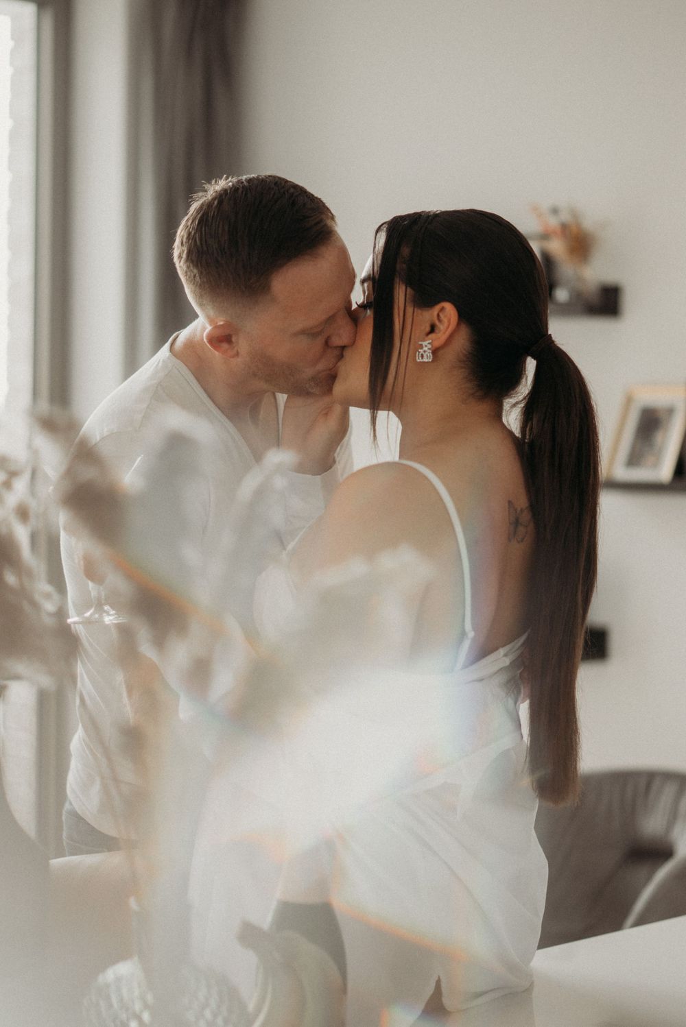 Romantic soft focus portrait of couple embracing in white clothing.