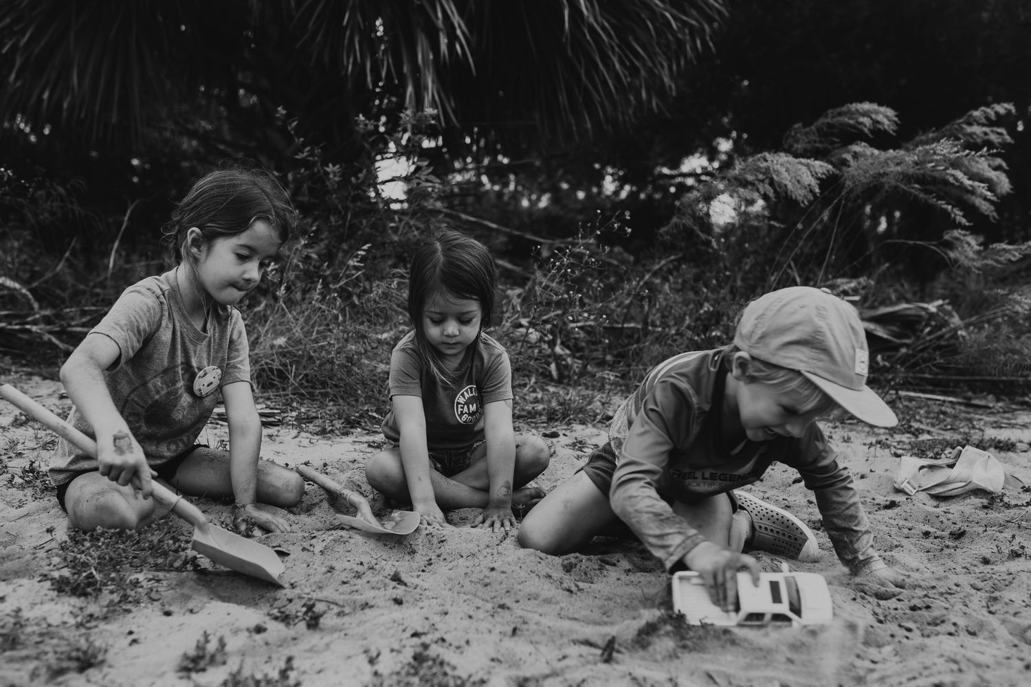 Vintage black and white photo of children playing together in the sand.
