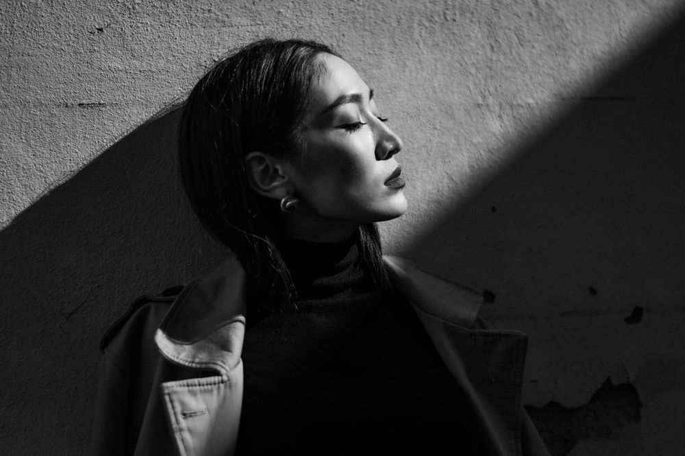 Dramatic black and white profile portrait with strong shadow play on a textured wall.