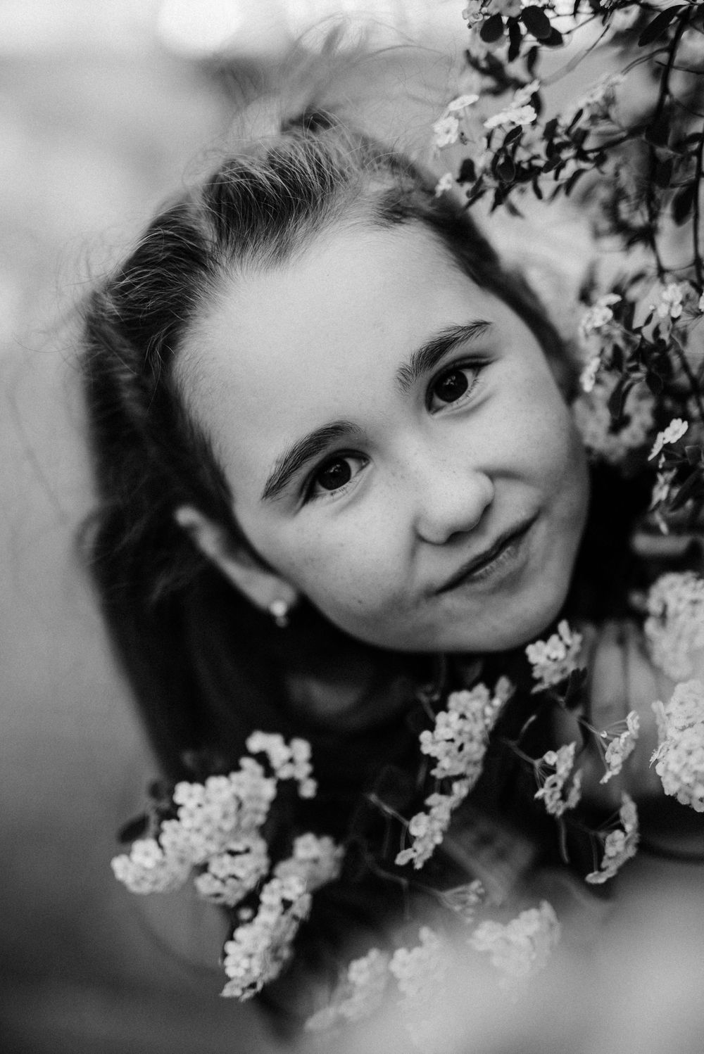 Black and white portrait among delicate spring blossoms with soft bokeh effect.