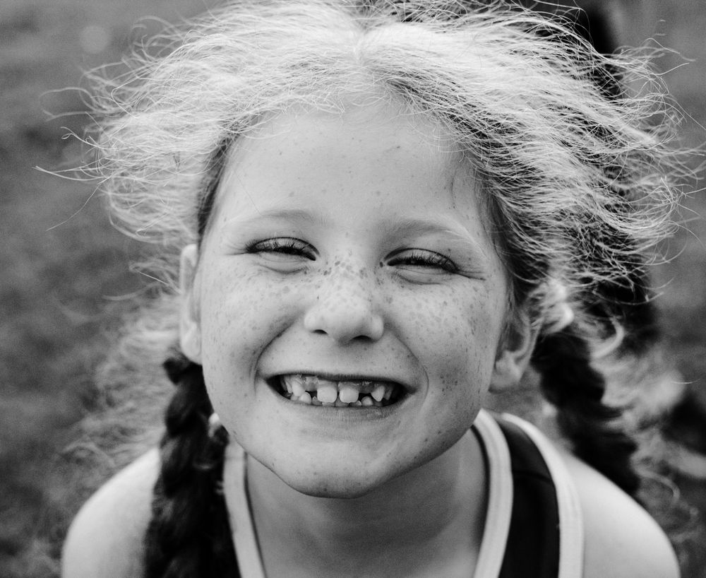 Series of black and white portraits capturing candid smiles and windswept hair.