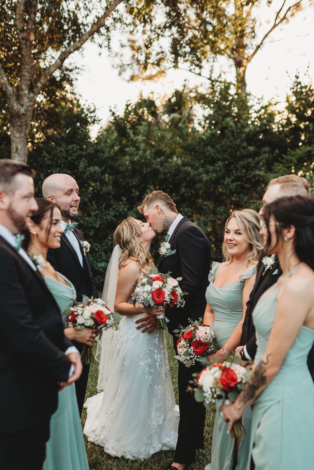 Intimate moment captured with wedding party in mint green and black attire holding floral bouquets.