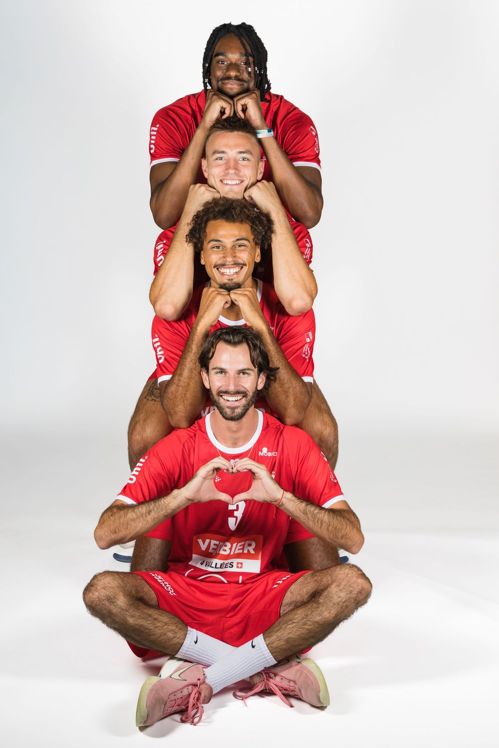 A creative photo sequence showing soccer players in red jerseys posing playfully in ascending stack formation.