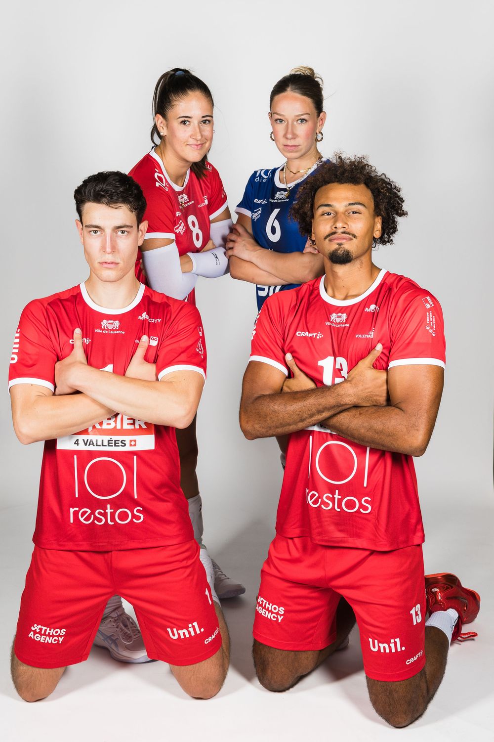 Team photo of volleyball players in red uniforms posing together against white background.