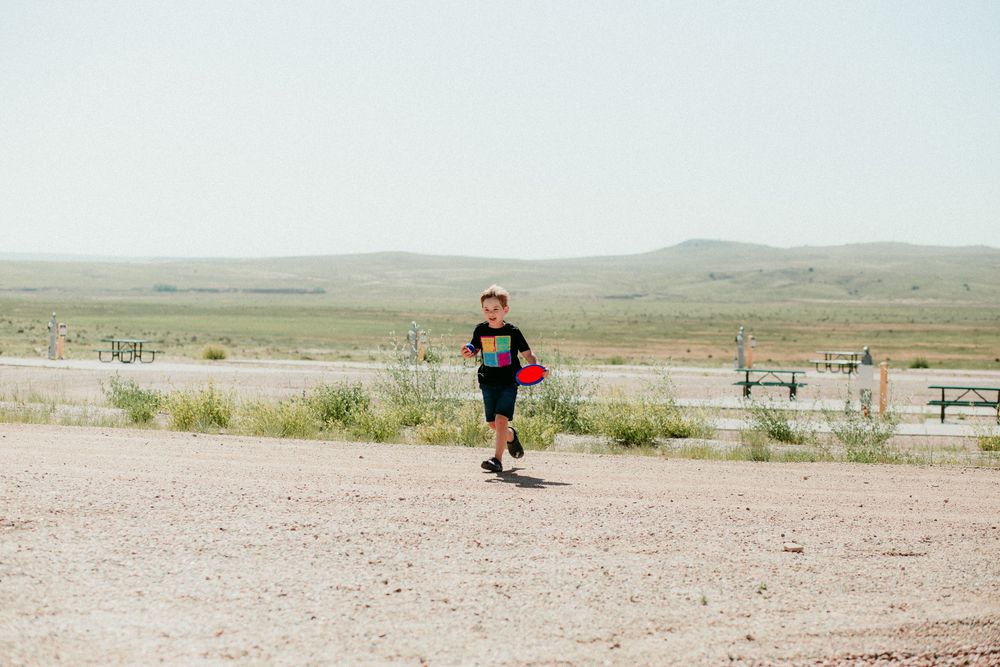 A runner exercising on a dusty trail in an arid desert landscape with mountains in the background.