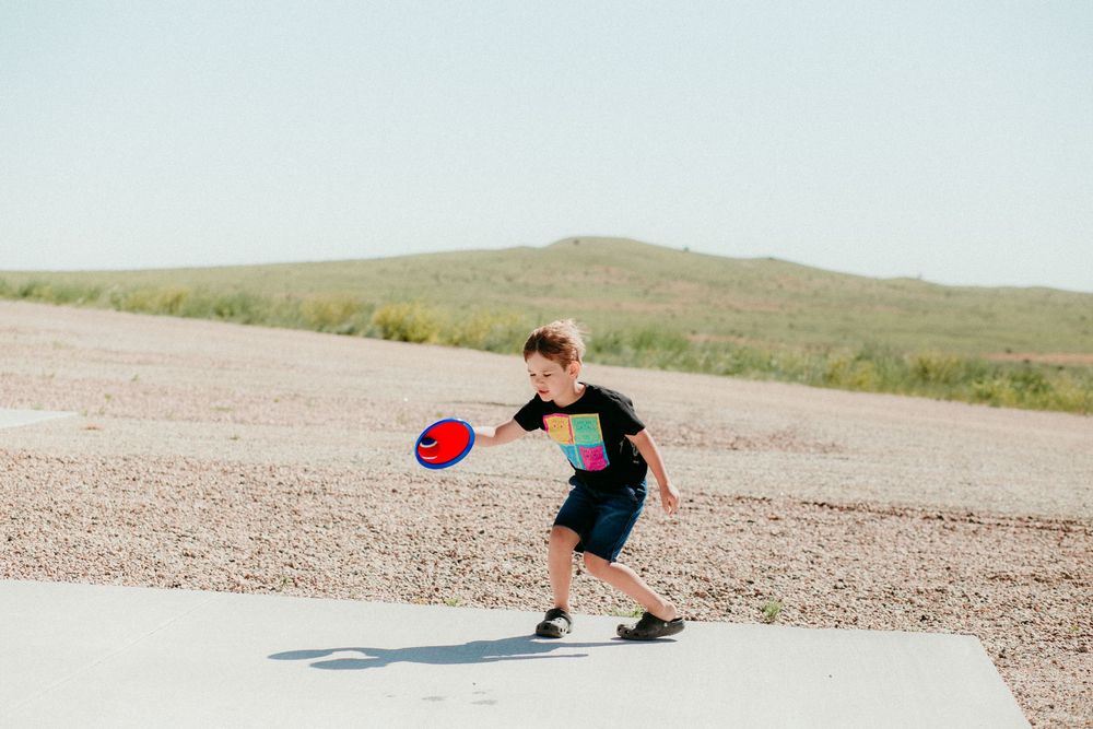 People playing ping pong on outdoor tables in a desert landscape with rolling hills in the background.